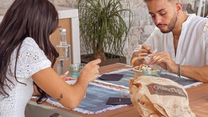 Two people dining at a wooden table with a stone wall background. - Al Borgo Luxury suite 01 (Abbasanta)