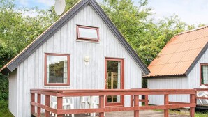 Et lille, etplans træhus med veranda og parabolantenne.