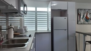 Une cuisine moderne équipée d’appareils électroménagers en acier inoxydable, d’un four encastré et d’une grande fenêtre avec des stores.
