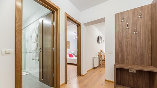 Un intérieur moderne avec une armoire en bois, une douche en verre et un coin repas agrémenté d’un coussin rouge.