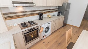 Une cuisine compacte équipée d’un four encastré, d’un four à micro-ondes et d’un lave-linge.