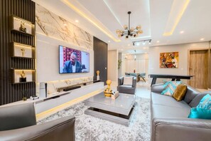 Un salon moderne avec un téléviseur à écran plat, une cheminée, un canapé et une table basse.