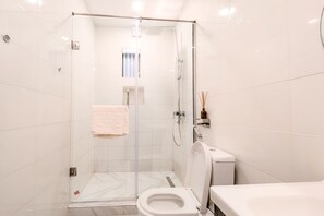Une salle de bain moderne avec une douche à parois de verre, des toilettes et un lavabo.