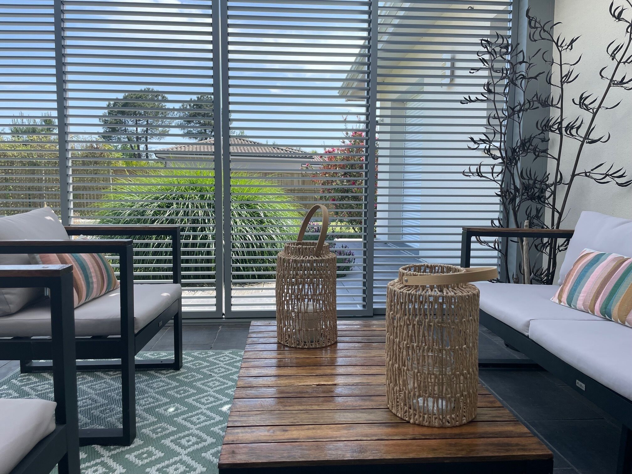 A modern living room with a sofa, two wicker baskets, and a patterned rug.