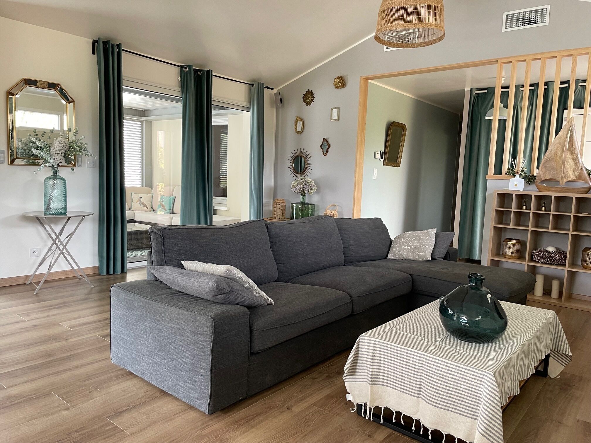 A modern living room with a grey sectional sofa, a small round table, and a striped tablecloth.
