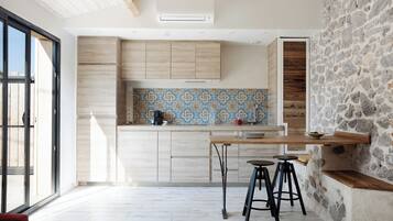 Une cuisine moderne avec des armoires en bois, un dosseret à motifs et un mur d’accent en pierre.