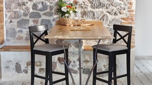 A rustic stone wall, a wooden table with two chairs, and a woven basket with flowers. - Pine Lodge and Spa (La Garde)