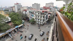 Une rue animée en milieu urbain, bordée d’immeubles, de boutiques et traversée par des véhicules.