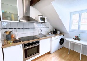 Een kleine keuken met een magnetron, oven, spoelbak en wasmachine.