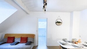 A modern living room with a sofa, dining table, and a view of the sea through a door. - Whole apartment 6p: apartment in residence - Campan, France (Campan)