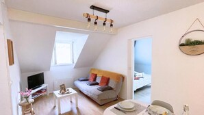 A modern living room with a sofa, a dining table set, a TV, and a ceiling light fixture. - Whole apartment 6p: apartment in residence - Campan, France (Campan)