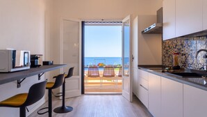 A modern kitchen with a view of the sea, a bar area with stools, and a dining area with chairs. - Villa Horama - Waterfront with Infinity Pool (Siracusa)