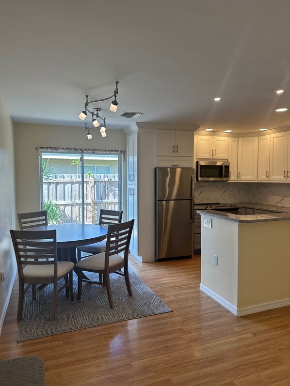 A modern kitchen with a central island, stainless steel appliances, and a dining area with a table and chairs.