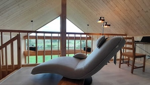 A cozy room with a high ceiling, a cushioned chair, a desk with a computer, and a view of the outdoors. - Villa Leone - spacious, breathtaking in harmony with nature (Nowe Warpno)