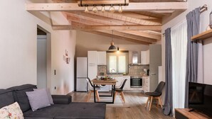 Ein modernes Wohnzimmer mit Sofa, Fernseher und Essbereich mit Tisch und Stühlen.