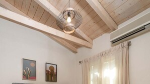 Ein Schlafzimmer mit einem großen Bett, Holzbalkendecke, einer Hängelampe und zwei Wandgemälden.