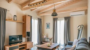 Ein modernes Wohnzimmer mit Holzboden, einem Flachbildfernseher, einer Couch, einem Couchtisch und einer Pendelleuchte.