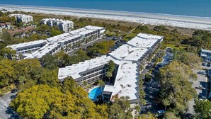 A coastal hotel with multiple buildings, a parking area, and a beach view. - Classic Coastal Condo, Oceanview, Short Walk to Coligny, & Free New Bikes! (Hilton Head Island)