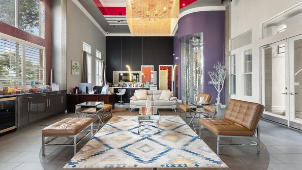 Un'ampia zona giorno con una grande finestra, un lampadario e una cucina moderna sullo sfondo.