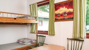 A bunk bed with a wooden table and chairs, a window with curtains, and a painting on the wall. - 4 Person Holiday Park Home in Grindsted (Grindsted)