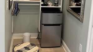 Eine kompakte Küche mit integriertem Kühlschrank, einer Kaffeemaschine und einer kleinen Essecke mit einem Hocker.