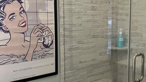 Ein Badezimmer mit Duschkabine aus Glas, Toilette und einem gerahmten Kunstwerk an der Wand.