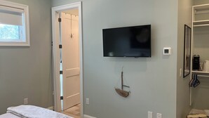 Ein Badezimmer mit einem an der Wand befestigten Fernseher, einem Handtuchhalter und einem Ablagefach mit Pflegeprodukten.