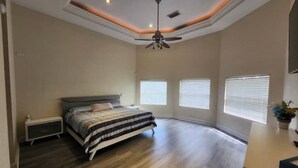 A bedroom with a bed, a nightstand, a ceiling fan, and three windows with blinds. - Margate Zen Paradise Water View (Margate)