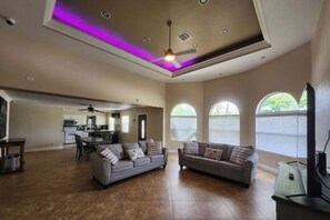 A spacious living room with two sofas, a dining area, and a kitchen in the background.