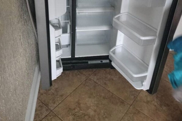 An empty refrigerator with multiple shelves and a freezer compartment.