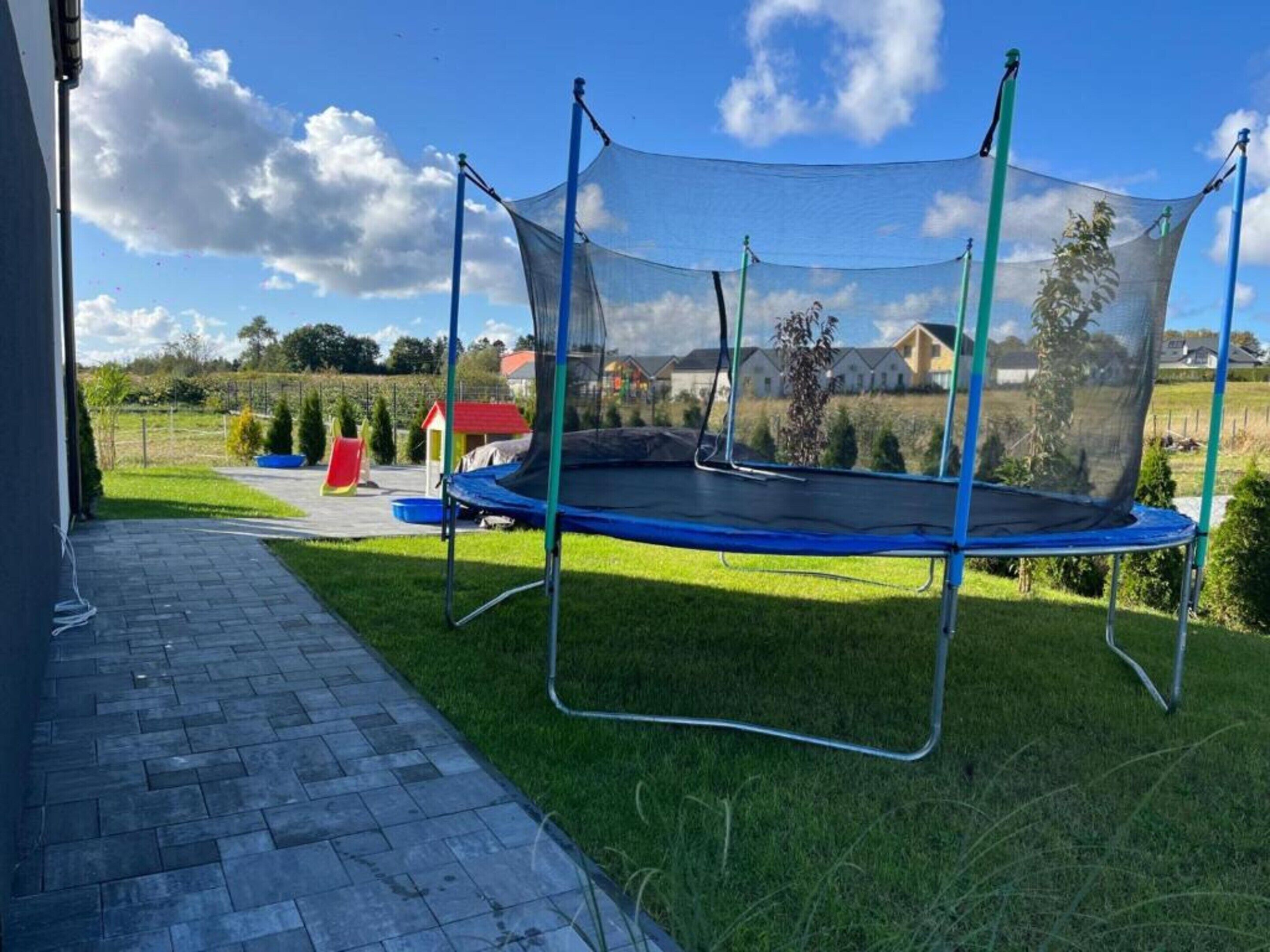 A trampoline with a safety net in a grassy outdoor area.