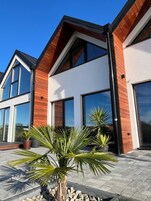 Una casa moderna de dos pisos con ventanas grandes y fachada de madera.