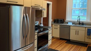 Una cocina moderna con electrodomésticos de acero inoxidable, piso de madera y un ventanal que proporciona luz natural.