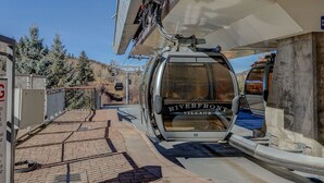 A cable car at Riverfront Village station with a clear view of the surrounding area, including trees and a paved path.