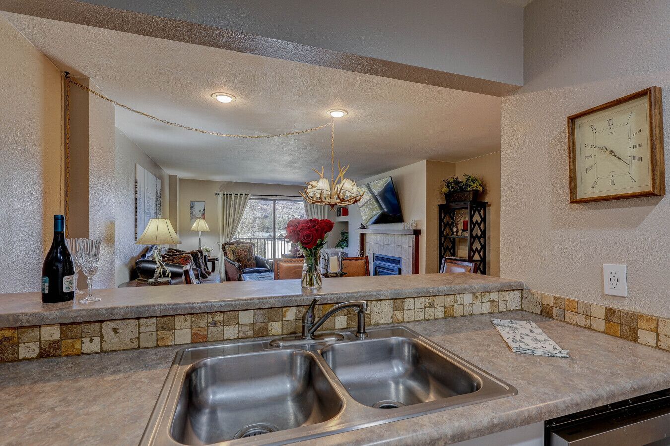 A kitchen with a double sink, a chandelier, and a clock on the wall.