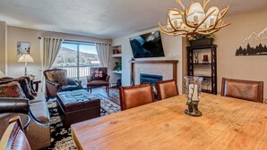 A spacious living room with a wooden dining table, leather sofas, and a fireplace.