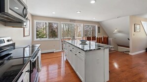 Una cocina moderna con una isla grande, electrodomésticos integrados y amplios ventanales que ofrecen vistas al exterior.