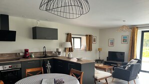 Et moderne køkken med spiseområde, fjernsyn og sofa.