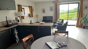 Et moderne køkken med spiseplads, sofa og tv.