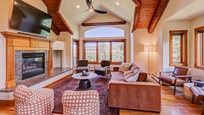 Un salón amplio con chimenea, asientos cómodos y grandes ventanales que ofrecen vistas al exterior.