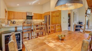 Una cocina amplia con armarios de madera, una mesa de comedor grande y una lámpara colgante.
