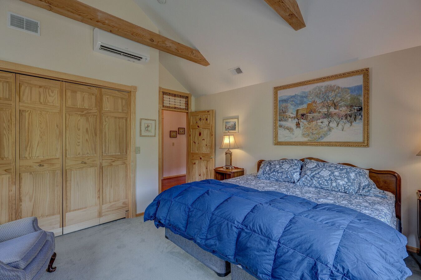 Une chambre avec un grand lit, une armoire en bois et un tableau accroché au mur.