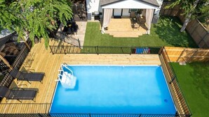 Quintal com piscina, deck de madeira e área de varanda coberta.