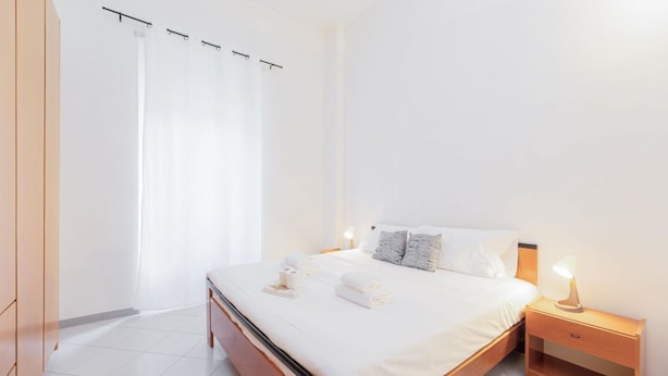 A bedroom with a bed, bedside table, and a curtain.