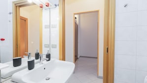 A modern bathroom with a large sink, two mirrors, and a wooden door.