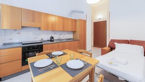 A compact kitchen with wooden cabinets and a dining area with a table set for two.