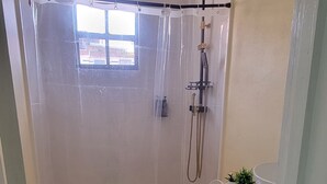 A bathroom with a shower, toilet, and a sink.