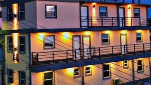 A multi-story building with balconies and exterior lighting.