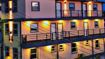 Un immeuble à plusieurs étages doté de balcons et d’un éclairage extérieur.