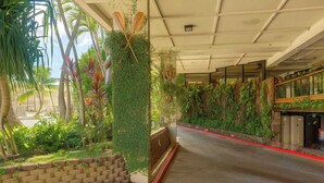 Une allée couverte avec un mur en briques, de la verdure et un espace aménagé avec des sièges.